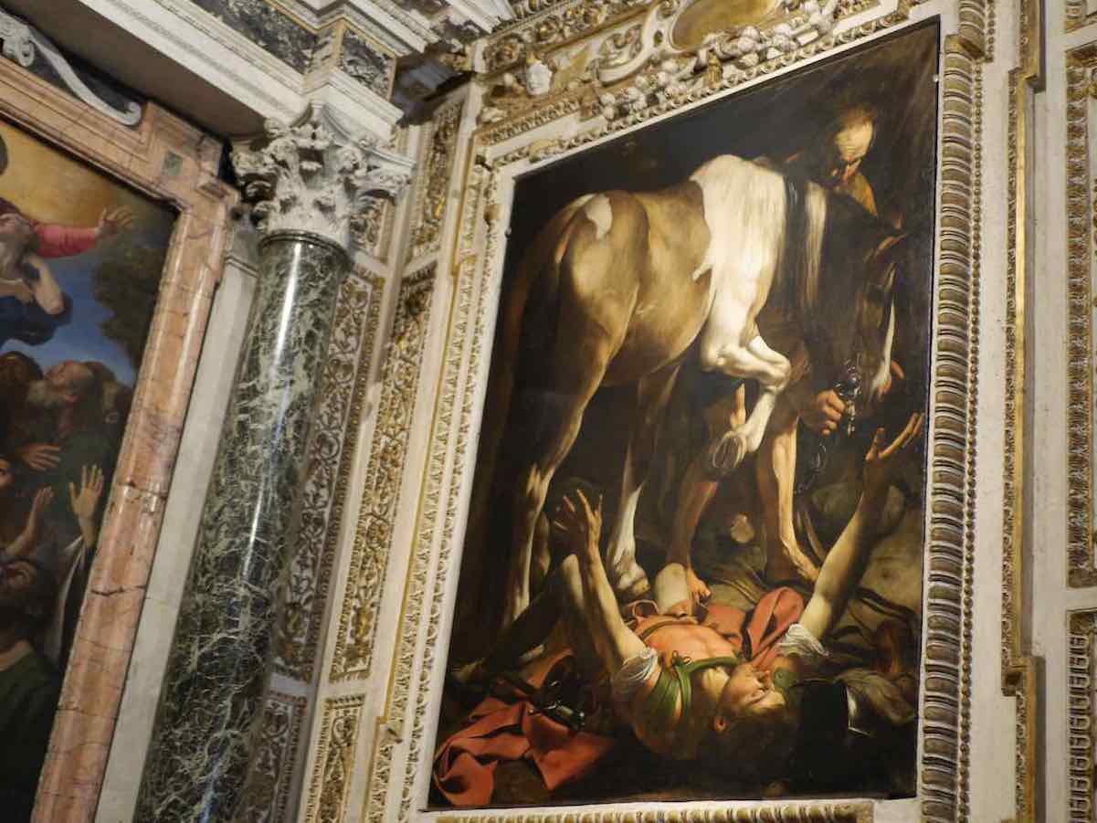"Conversion on the Way to Damascus" by Caravaggio: A powerful depiction of Saul's (later Paul) divine encounter, with a heavenly beam illuminating his astonished face as he lies on the ground, his sword cast aside, symbolizing his submission and imminent conversion. The painting is keps in the Church of Santa Maria del Popolo in Rome's Piazza del Popolo